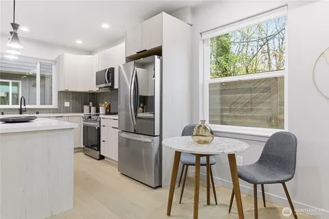 a kitchen with stainless steel appliances granite countertop a stove a refrigerator a kitchen island a table and chairs in it