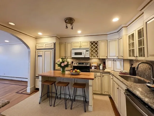 a kitchen with stainless steel appliances kitchen island granite countertop a refrigerator and a stove top oven