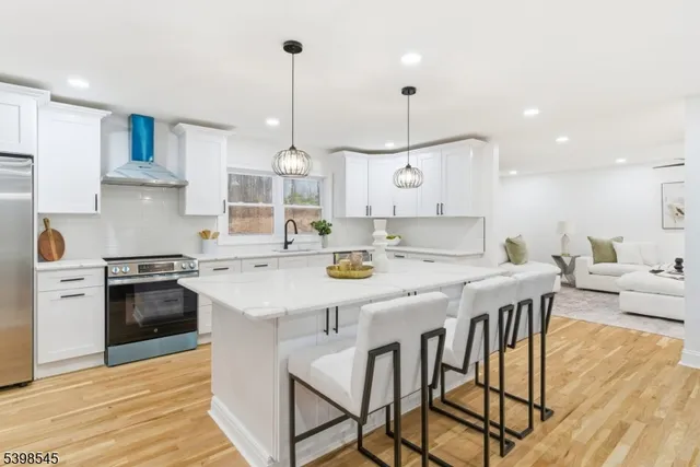 a kitchen with stainless steel appliances kitchen island granite countertop a stove a sink a dining table and chairs with wooden floor