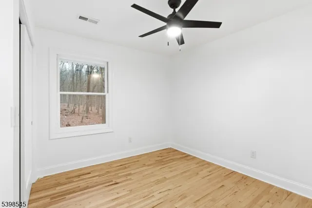 an empty room with a window and ceiling fan