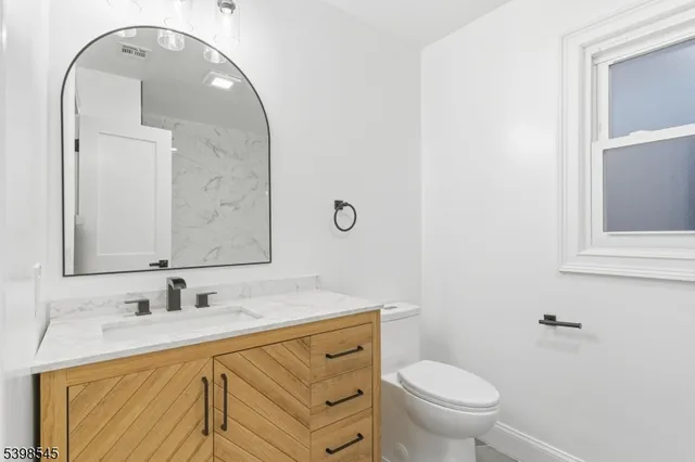 a bathroom with a granite countertop toilet a sink and a mirror