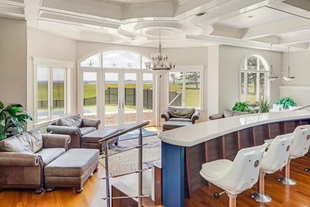 a dining hall with couches a flat tv screen and potted plant with kitchen view