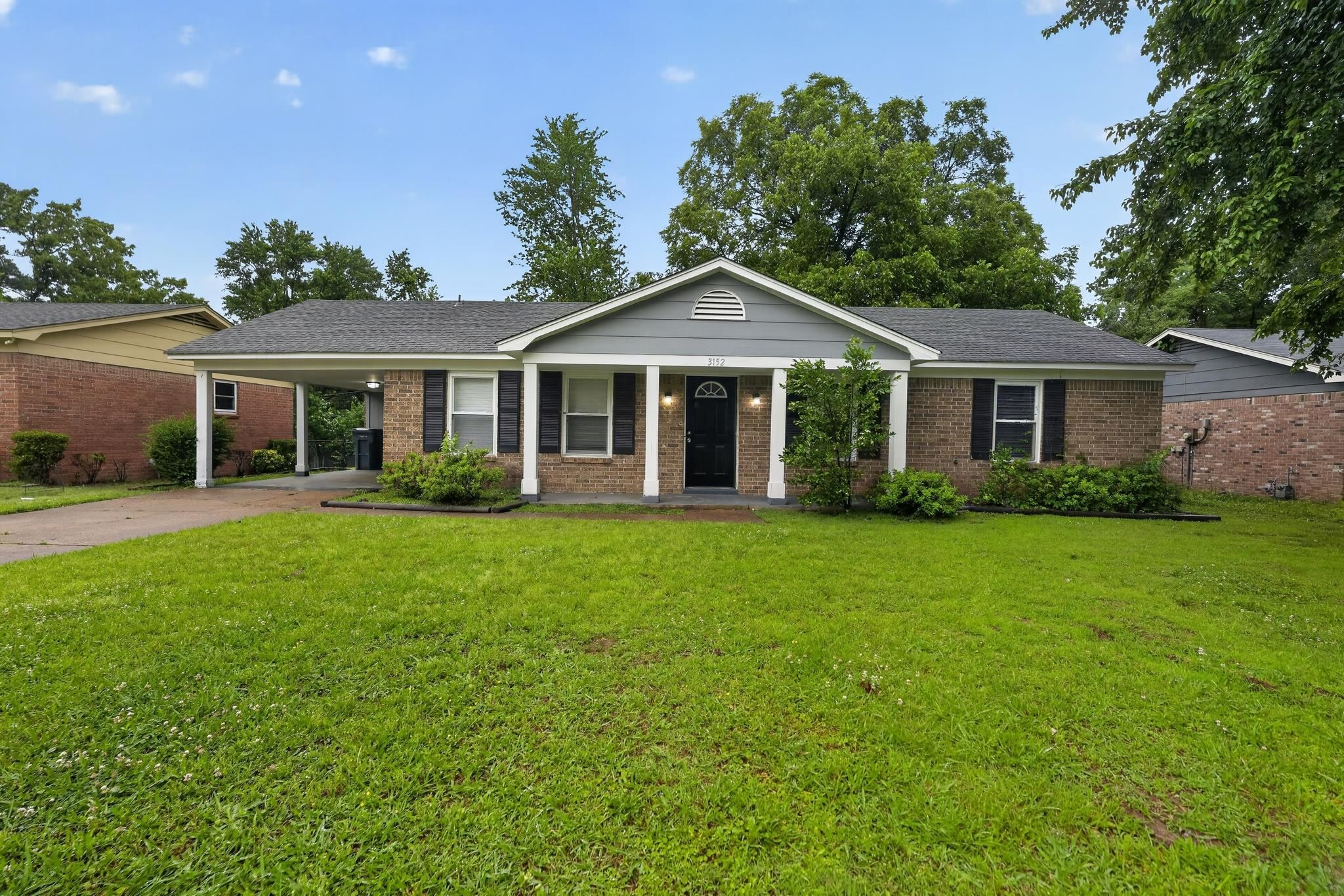 Brick and siding exterior featuring a covered carport, black shutters, and an inviting front entry with white columns