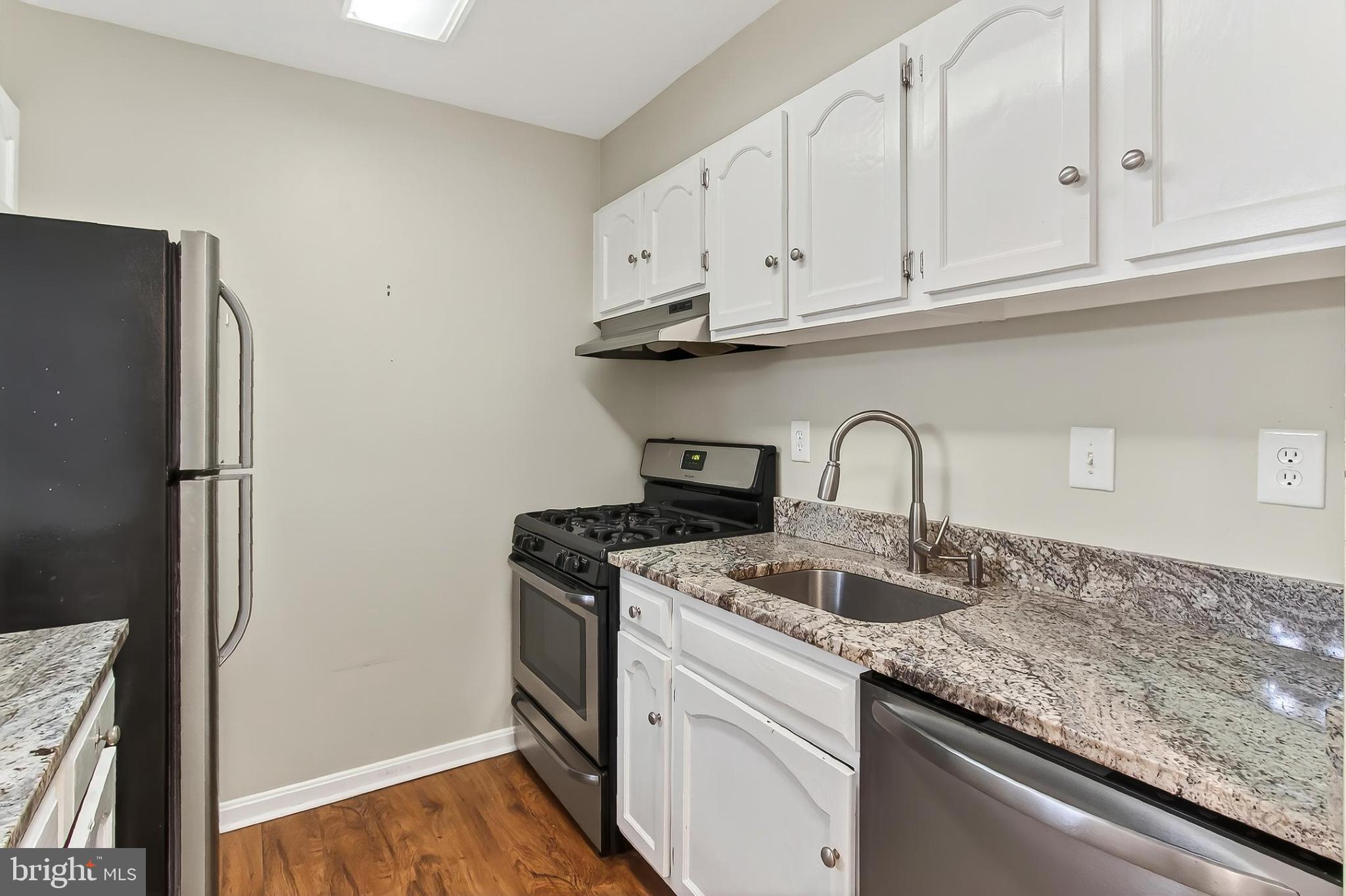 5833 Cove Landing Road, Unit 304 Burke, VA 22015 - Photo 21 of 34 a kitchen with granite countertop white cabinets and a stainless steel appliances