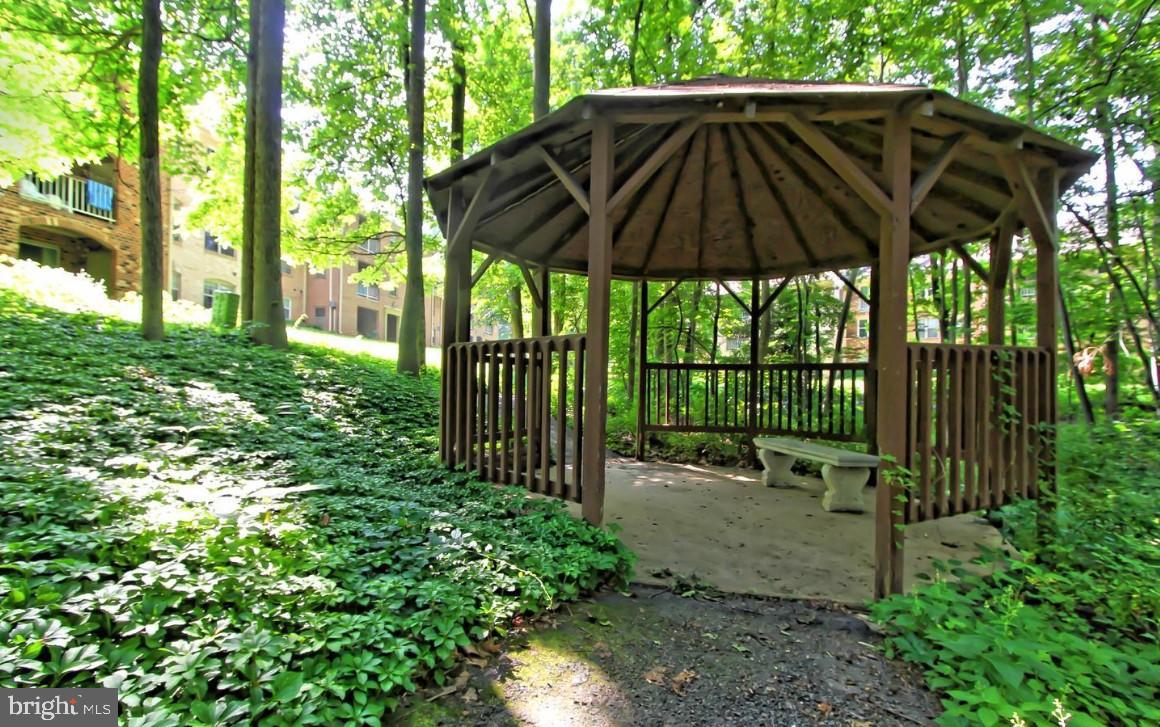 5833 Cove Landing Road, Unit 304 Burke, VA 22015 - Photo 31 of 34 a backyard of a house with table and chairs under an umbrella