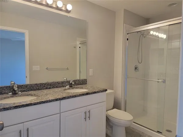 a bathroom with a granite countertop sink toilet and shower