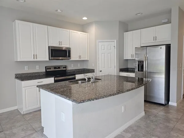 a kitchen with stainless steel appliances granite countertop a sink a stove a refrigerator a microwave and cabinets