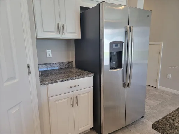 a kitchen with metallic refrigerator freezer and a granite countertops