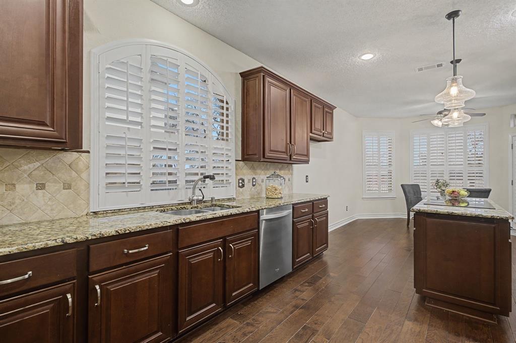 2705 Wind Ridge McKinney, TX 75072 - Photo 18 of 40 a kitchen with stainless steel appliances granite countertop a sink dishwasher stove and oven with wooden floor
