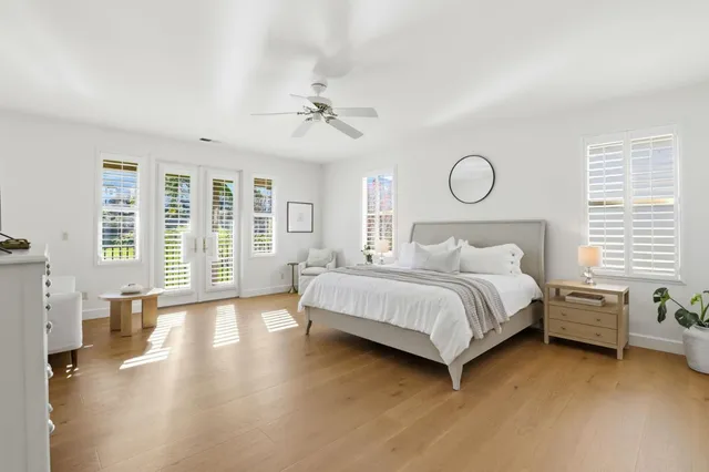 a bedroom with a large bed wooden floor and windows