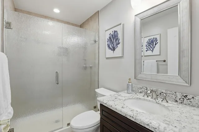 a bathroom with a granite countertop sink a toilet and shower