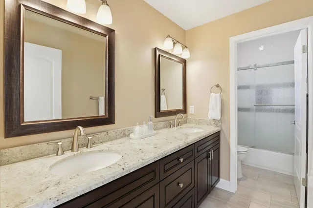 a bathroom with a granite countertop double vanity sink and a mirror