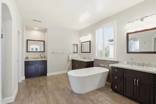 a spacious bathroom with a tub double sink and mirror