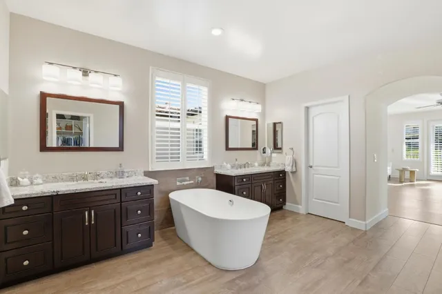 a bathroom with a granite countertop sink and mirror bathtub
