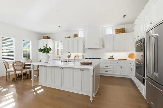 a kitchen with white cabinets and wooden floors