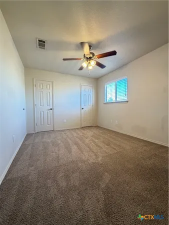 an empty room with windows and fan