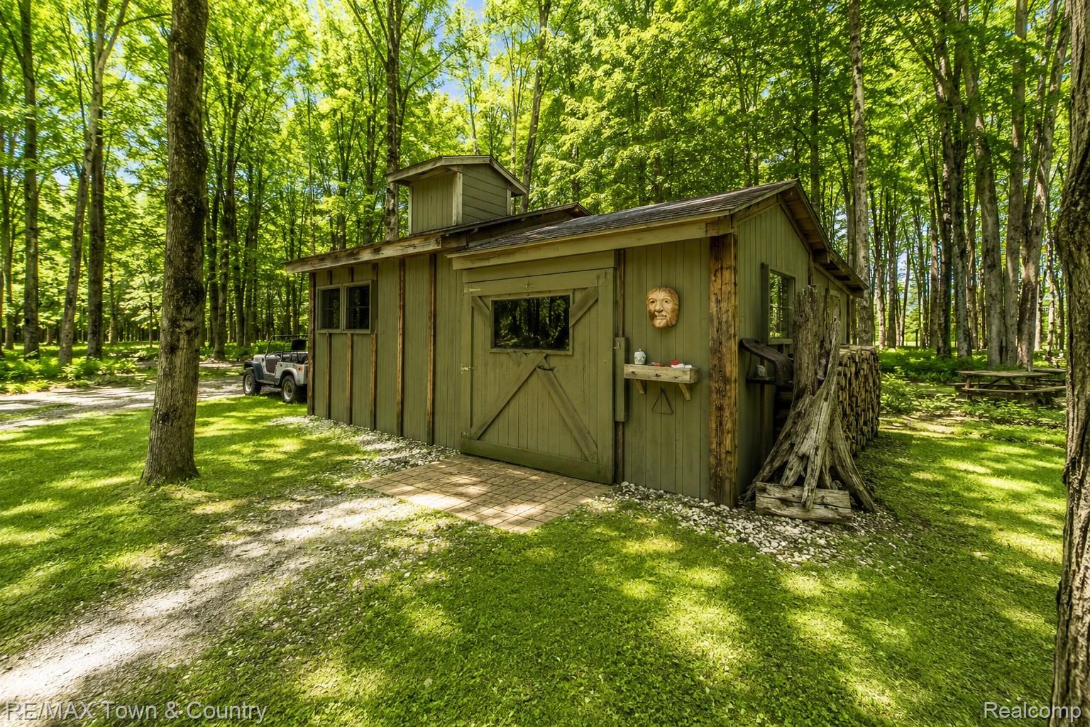 1293 Bellinger Road Gladwin, MI 48624 - Photo 16 of 27 Wood-sided structure with cupola, surrounded by mature trees and a grassy expanse