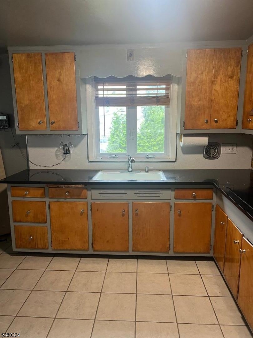a kitchen with granite countertop a sink a stove top oven cabinets and a window