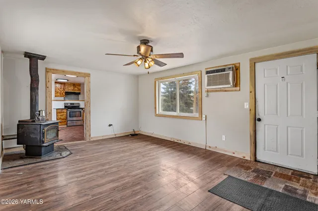 a view of an empty room with a window and wooden floor