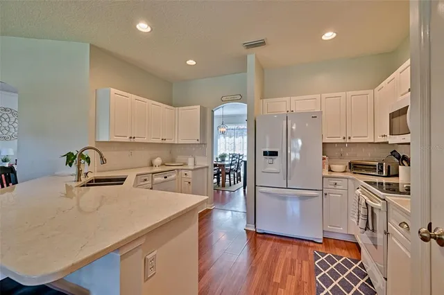 a kitchen with a refrigerator a sink and white cabinets