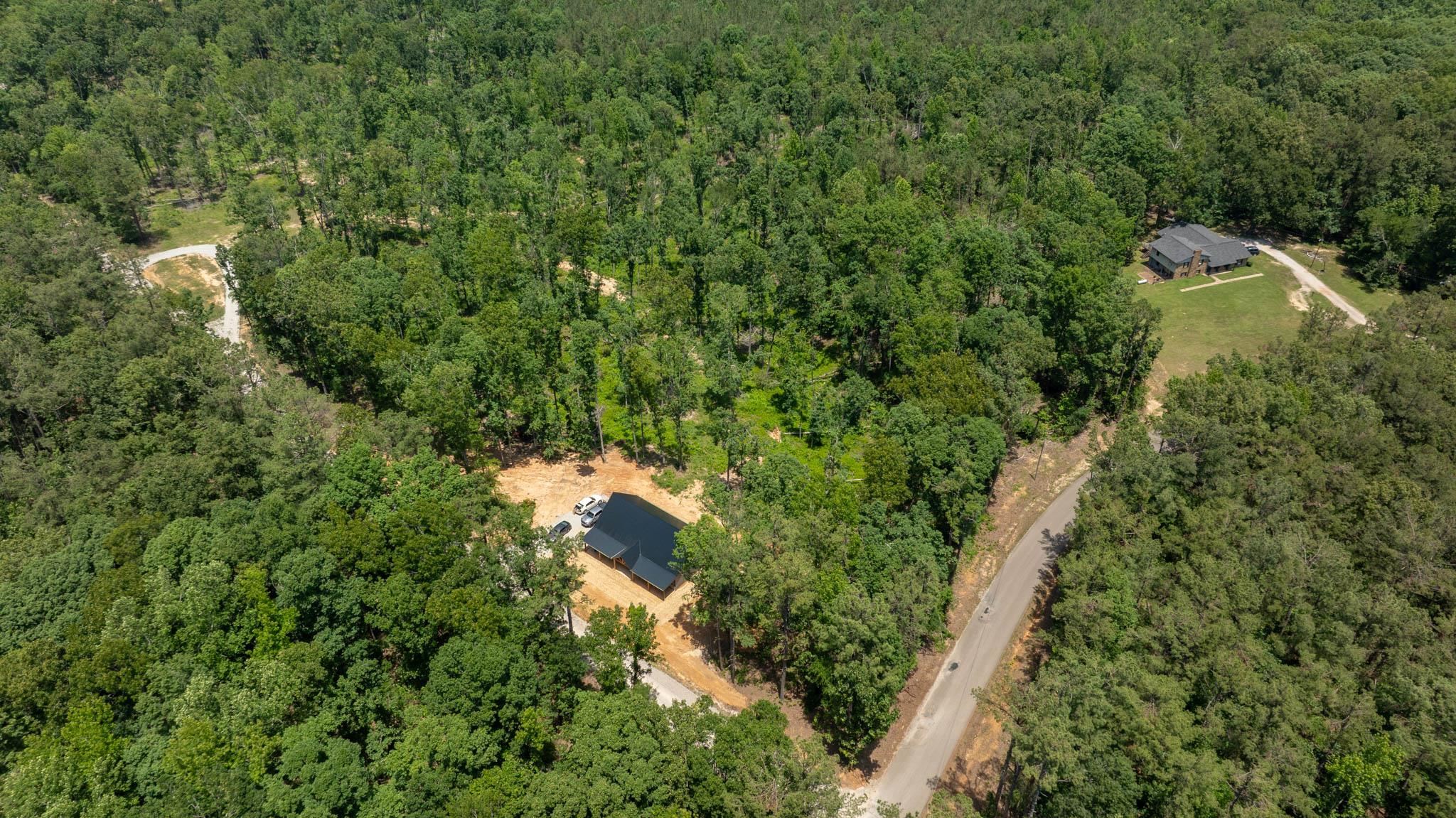 37 William Teague Lane Ramer, TN 38367 - Photo 39 of 39 Wooded acreage featuring a partially cleared lot with a modern black-roofed structure under construction