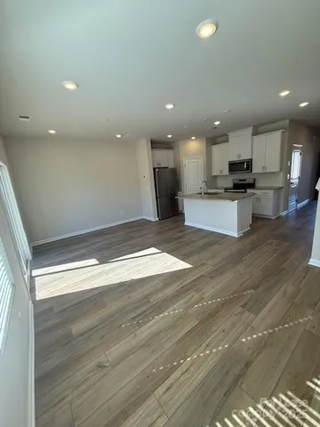 a view of kitchen with kitchen island granite countertop living room and hallway