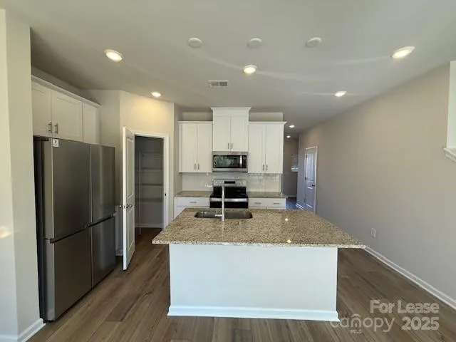 a kitchen with granite countertop a refrigerator and a stove top oven