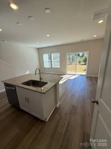 a kitchen with stainless steel appliances granite countertop a sink a stove and wooden floors