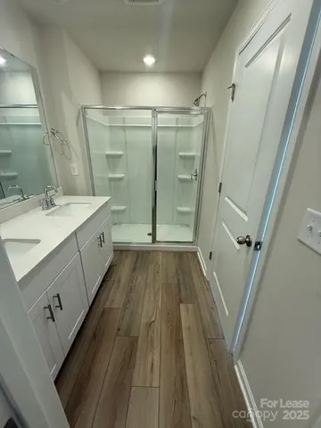 a spacious bathroom with a double vanity sink a toilet a mirror and shower
