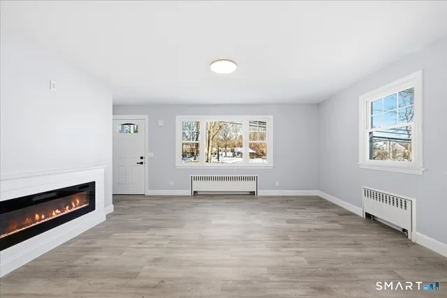 a view of an empty room with a window and fireplace