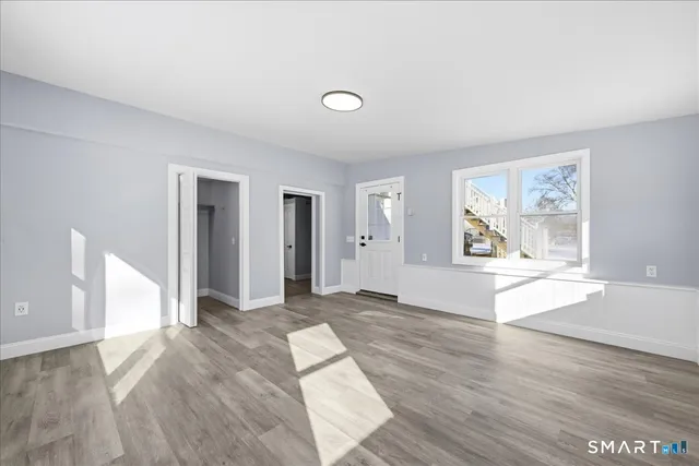 a view of an empty room with window and wooden floor