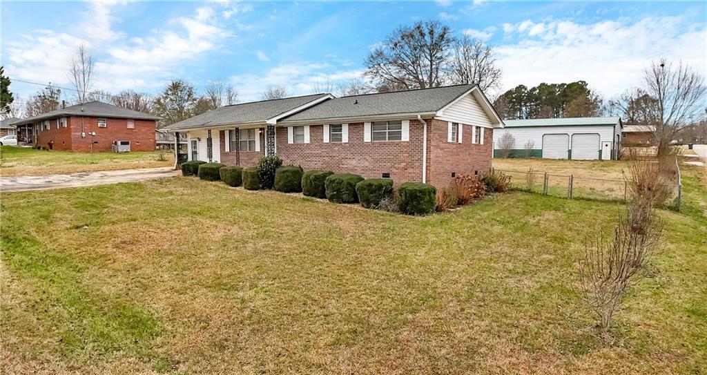 a view of a white house next to a yard with plants and large trees