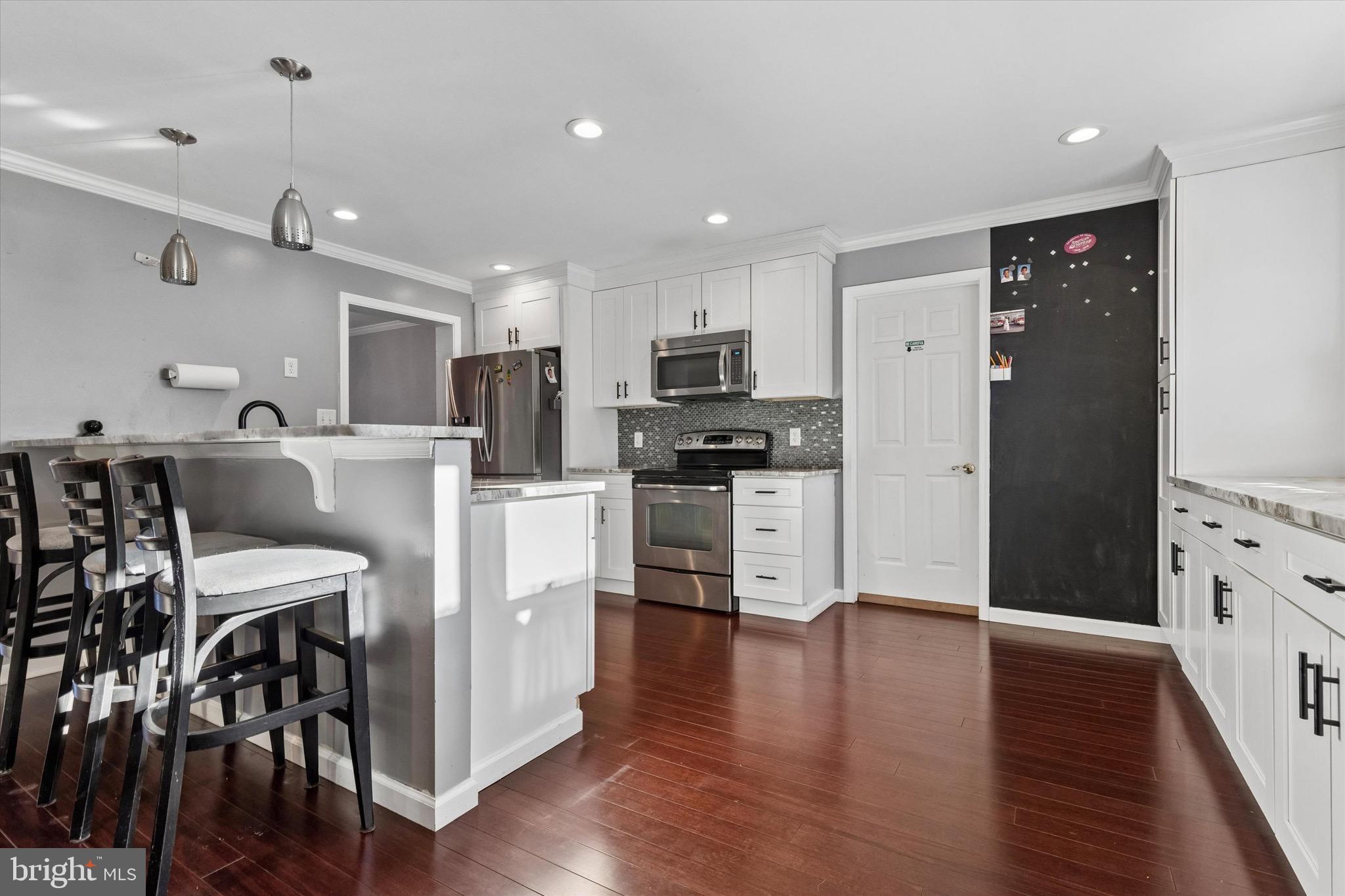 1126 Plowshare Road Blue Bell, PA 19422 - Photo 7 of 30 a kitchen with stainless steel appliances kitchen island granite countertop a refrigerator a stove a microwave oven a sink with island and chairs with wooden floor