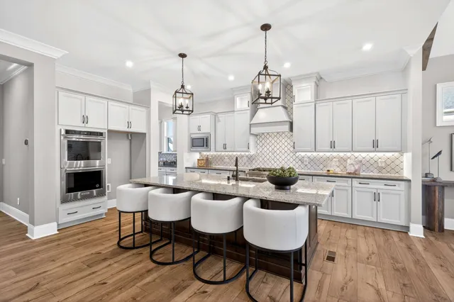 a large kitchen with a counter space a sink stainless steel appliances and living room view