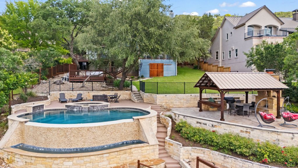 10800 Beach Road Leander, TX 78641 - Photo 3 of 39 Discover a private outdoor oasis with a beautiful tiered pool and a fully equipped outdoor kitchen under a spacious gazebo.
