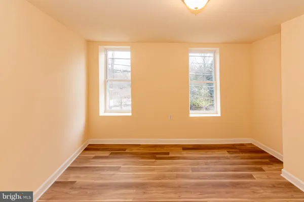 a view of a hallway with wooden floor and a bathroom