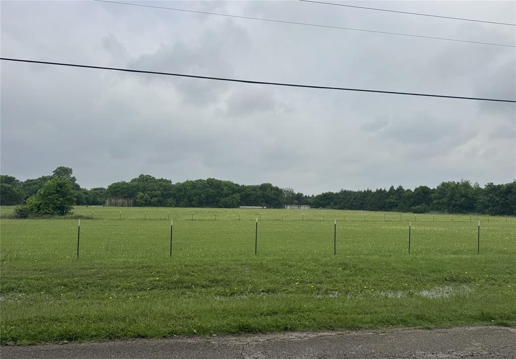 2509 Grace Lane Lancaster, TX 75146 - Photo 1 of 6 Expansive green field with T-posts, bordered by mature trees