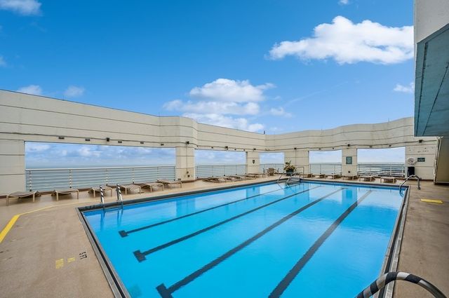 a living room with couches and a view of kitchen appliances