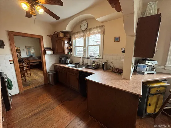a kitchen with stainless steel appliances granite countertop a refrigerator a sink dishwasher a stove oven and a dining table with wooden floor