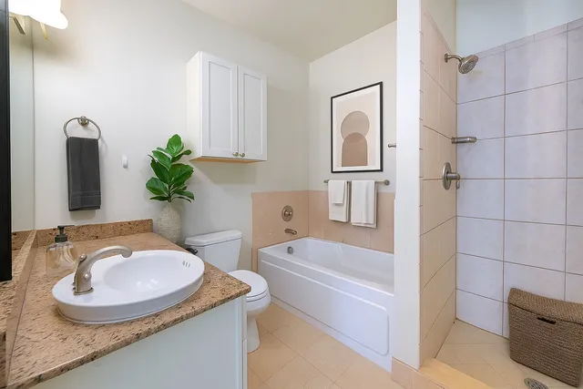 a bathroom with a granite countertop sink a toilet a mirror and bathtub