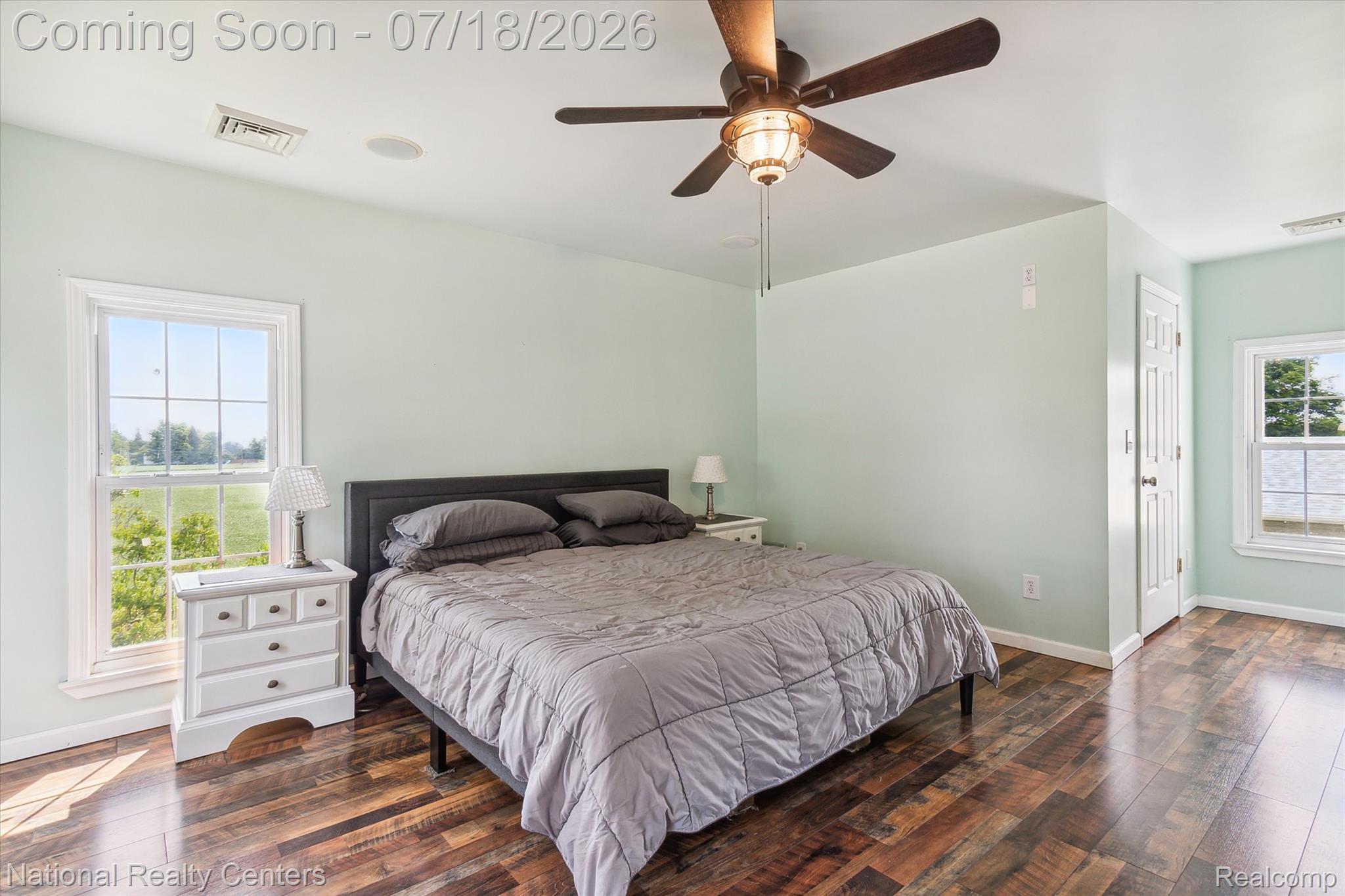 9589 Clinton Macon Road Tecumseh, MI 49286 - Photo 33 of 48 Bedroom featuring wood-finish flooring, two windows with outdoor scenery, a ceiling fan with integrated lighting, and a built-in ceiling speaker