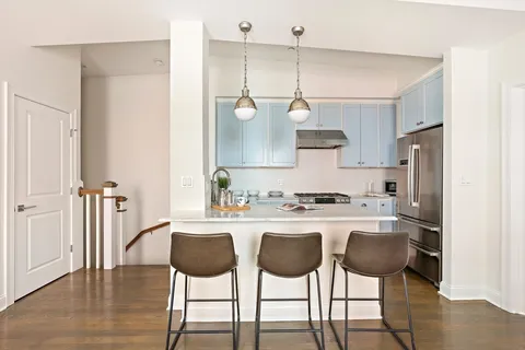 a kitchen with stainless steel appliances a dining table chairs and white cabinets