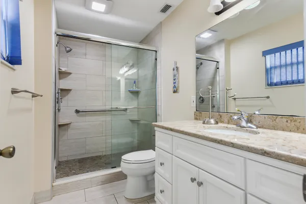 a bathroom with a granite countertop sink toilet and shower