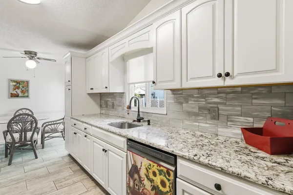 a kitchen with granite countertop white cabinets and white appliances