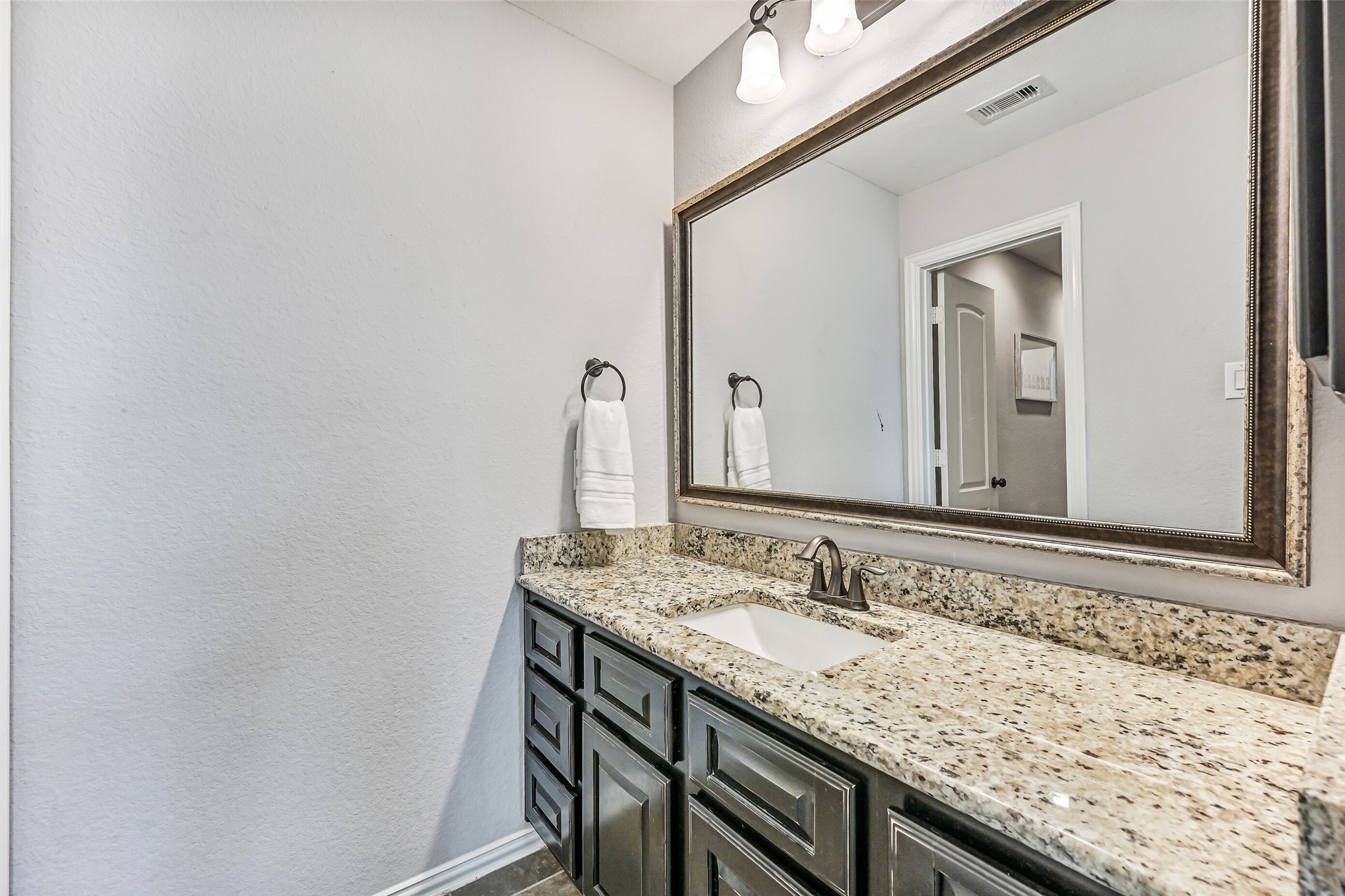 1008 Point Isabel Lane Friendswood, TX 77546 - Photo 41 of 50 A closer look at the other vanity in the Jack & Jill bathroom highlights the granite countertops, rectangular basin sink, oil rubbed bronze hardware, framed mirror, ample storage, and durable finishes designed for everyday use.