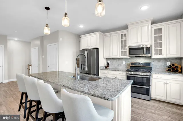a kitchen with kitchen island granite countertop a stove a sink a dining table and chairs