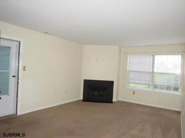 an empty room with a fireplace and windows