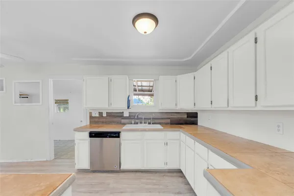 a kitchen with granite countertop a sink cabinets stainless steel appliances and a window