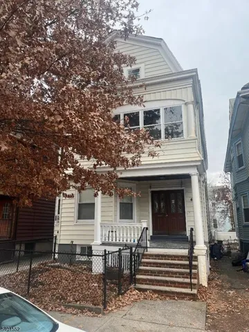 a view of a house with a yard and large tree