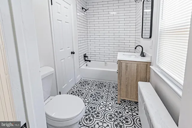 a bathroom with a granite countertop toilet a sink a mirror and shower